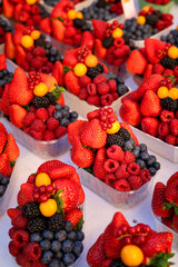 Delicioso combo de frutos rojos en mercado callejero: fresas, arándanos, moras y otras frutas...