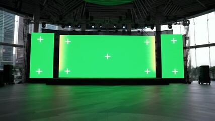 Empty Modern Event Stage with Large Green Screen LED Wall and Side Displays, Ready for Virtual Content and Presentations