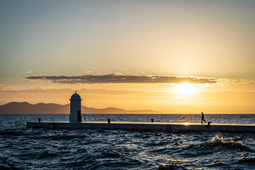 Hermosa postal del muelle de Zadar al atardecer, con la silueta de una persona caminando en el.