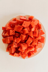 A plate filled with vibrant red watermelon cubes showcases the abundant, juicy fruit, perfect for a...