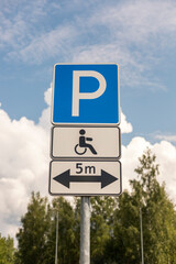 A sign displays parking regulations for accessible spaces with a wheelchair symbol, located under a...