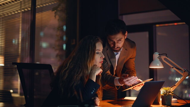 Young entrepreneurs analyzing goals night shift in dark office watching screen - Powered by Adobe