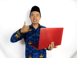 government worker man wearing kopri blue batik uniform holding a laptop, He is smiling and giving a...