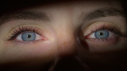 Woman opening her beautiful blue eyes, looking at the camera smiling, while the light illuminated...