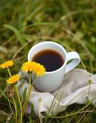 Summer morning among nature outdoor concept. Fresh composition with coffee cup and yellow dandelions on gentle, blurry, natural background with copy space. Slow down, coffee time, simple calm life, 