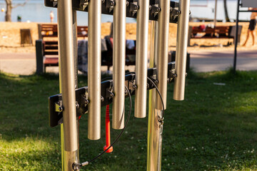 A unique musical structure made of metal tubes stands in a park by the water, offering a creative...