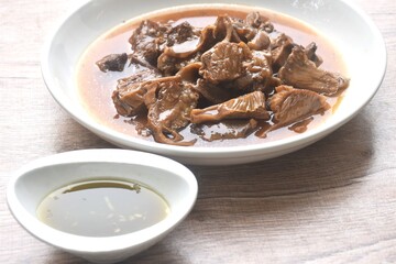 slice braised pork stew in herb brown soup dipping chili and sour sauce on plate