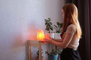 young redhead woman using salt lamp at home