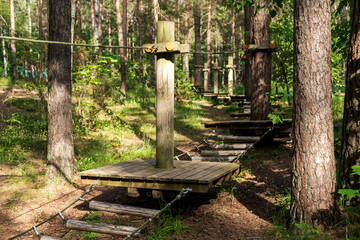 Wooden platforms connect via ropes, creating an engaging climbing pathway among tall trees,...