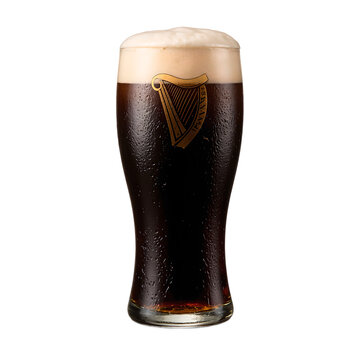 A close up of a glass of rich dark Guinness Stout with a creamy white foam isolated on white Perfect for beer and beverage concepts, isolated