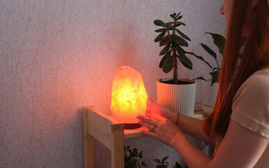 young redhead woman using salt lamp at home