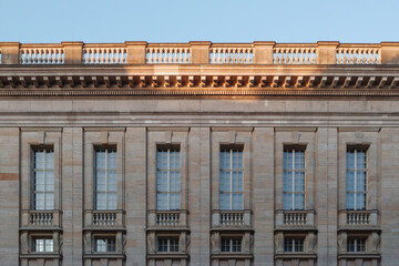 The symmetrical facade of a grand neoclassical building, illuminated by the warm light of the...