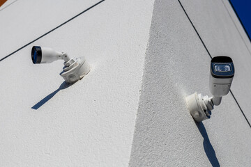 Surveillance cameras are securely installed at the corner of a building, capturing activity under...