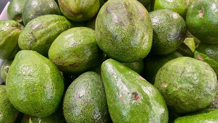 Fresh green avocados on a textured surface.