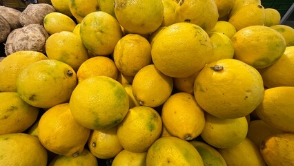 A large pile of freshly harvested lemons in a market.