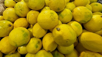 A large pile of freshly harvested lemons in a market.