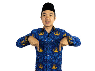 An Indonesian male civil servant wearing a blue Korpri batik uniform poses confidently pointing up,...