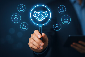 Hand holding magnifying glass with handshake icon and user profile symbols, business connection