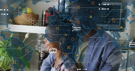 World map appearing over woman and man embracing in kitchen, showing icons for tech connectivity - Powered by Adobe