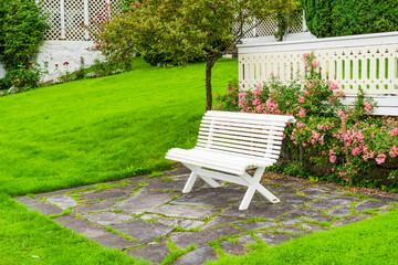 A white bench surrounded by roses in Balestrand, Norway