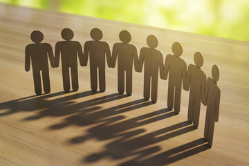 Wooden human figures holding hands in unity casting long shadows on wooden surface with bright light background representing community support concept. 3D Rendering