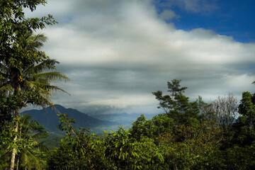 Lush Green Mountainscape Under a Cloudy Sky A Tropical Paradise View