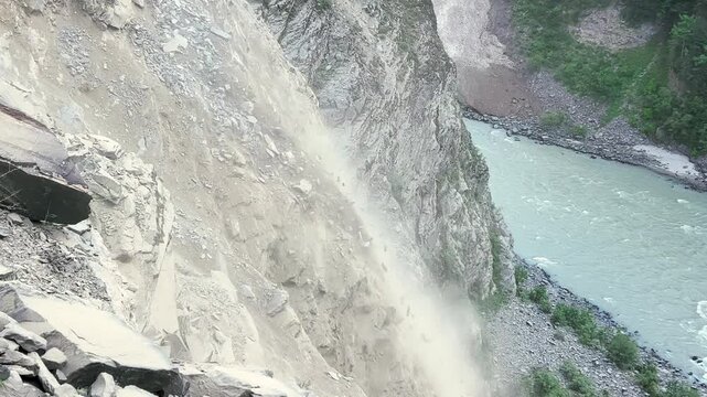 4K shot of rocks falling from the mountain due to landslide after heavy rains in the mountains during the monsoon season as seen from Manali in Himachal Pradesh, India. Rubble falls from the cliff.