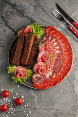 Assorted sausage platter on a plate. Different types of sausages – smoked, boiled, salami, and dry-cured – neatly arranged as an appetizing snack. Traditional meat dish served at festive tables, resta