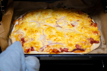 Hot Cheese and Onion Pizza Taken Out of Oven Using Mitt