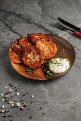 Close-up of traditional Ukrainian potato pancakes served with sour cream on a rustic ceramic plate....