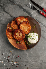 Close-up of traditional Ukrainian potato pancakes served with sour cream on a rustic ceramic plate....