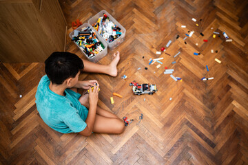 Child playing with colorful building blocks on hardwood floor