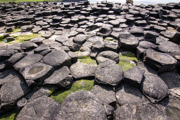 Hexagonal basalt columns at Giants Causeway Northern Ireland with sunburst sky evoking the legend of a giants causeway between Ireland and Scotland