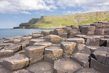 Hexagonal basalt columns at Giants Causeway Northern Ireland with sunburst sky evoking the legend of a giants causeway between Ireland and Scotland
