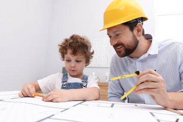 Choice of profession. Father and his son with dividers exploring engineering drawings at table...