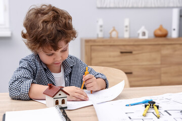 Choice of profession. Little kid with divider and engineering drawing at table indoors