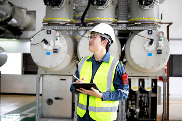 Industrial Engineer Wearing Safety Gear Checks Equipment in High-Tech Electrical Facility