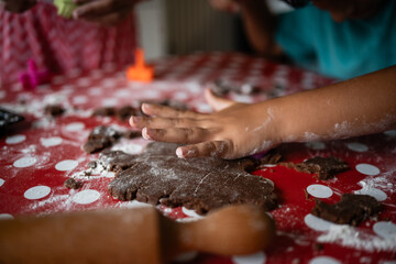 Children making cookies with chocolate dough on red table