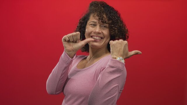 Hispanic woman wearing pink shirt pointing thumb to chest in studio; confidence empowerment positivity. - Powered by Adobe