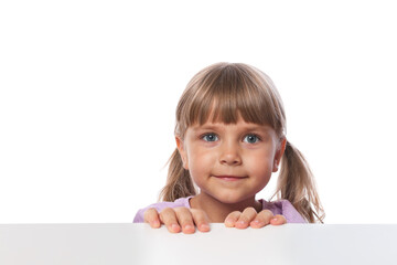 Curious little girl peeking over table against white background