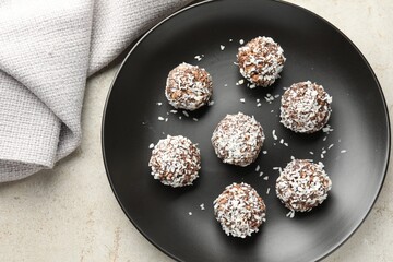 Tasty chocolate candies with coconut flakes on light table, top view