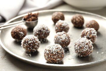Tasty chocolate candies with nuts and coconut flakes on light table, closeup