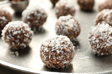 Tasty chocolate candies with nuts and coconut flakes on table, closeup