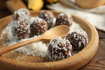 Tasty chocolate candies with nuts and coconut flakes on wooden table, closeup