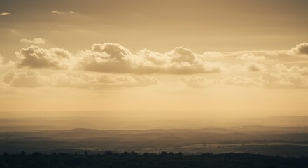 Fototapeta premium Golden hour sunlight illuminates a vast landscape with soft, diffused clouds, creating a serene and breathtaking natural vista
