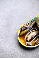 Sprats in tin can on grey textured table, top view
