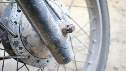 Closeup view of a rusty, weathered bicycle hub and spokes covered in dust and dirt