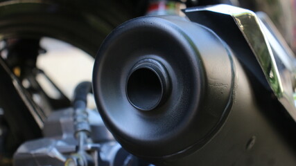 Closeup of a motorcycle exhaust muffler with a matte black finish, showcasing the outlet tip and...