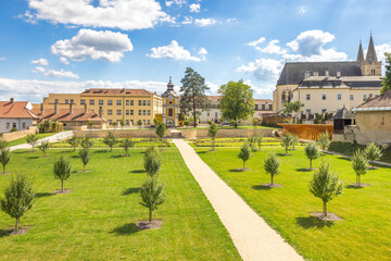 Fototapeta premium Spisska Kapitula, an ecclesiastical town in region of Spis in Slovakia, Europe. Picturesque European complex featuring manicured lawns, historic buildings, and a bright blue, cloudy sky.