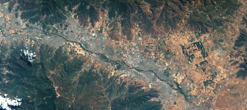 Aerial view of river valley landscape with mountains and fields for geography and environment studies